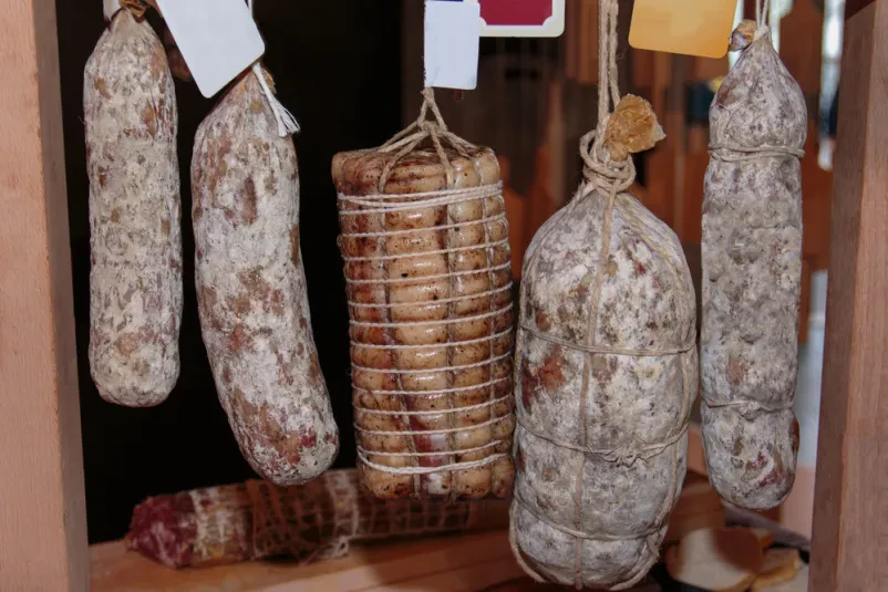 Suhe salame in druge suhe mesnine so obešene ter pripravljene za prodajo v mesnici.