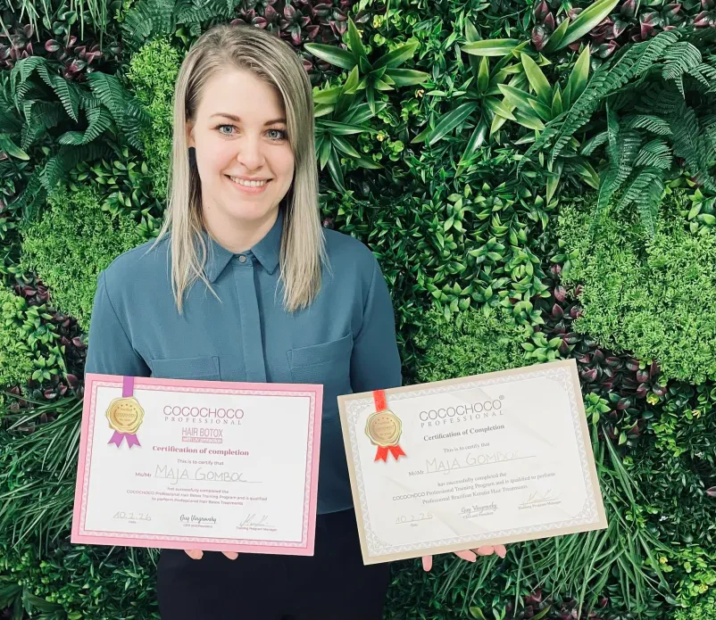 Frizerka s certifikati, ki prikazujejo, da je usposobljena za kvalitetno nego las.