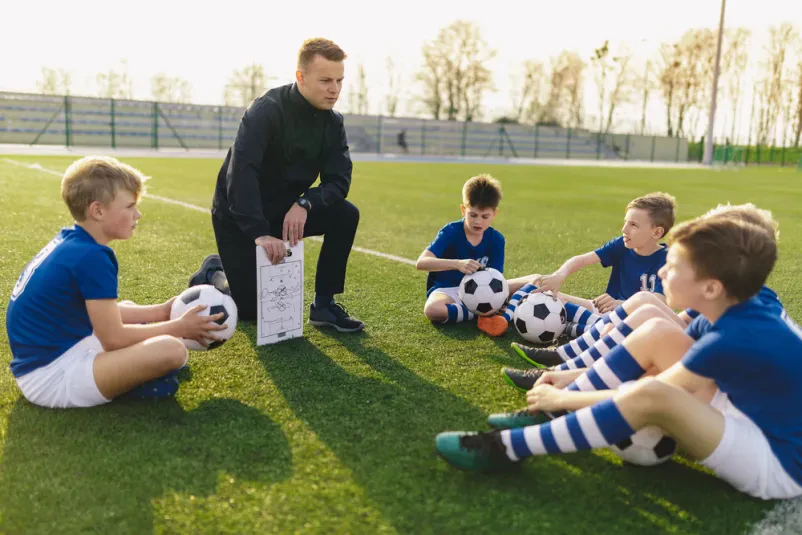 Fant trenira dribling med stožci Odločen mlad fant z žogo spretno dribla med stožci na nogometnem igrišču, kar je pomemben element vadbe, ki jo nudi nogometni trener Kočevje, Dolenjska.