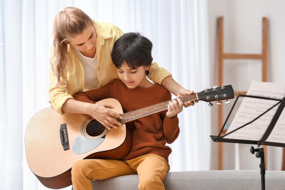 Deček se uči igrati na kitaro