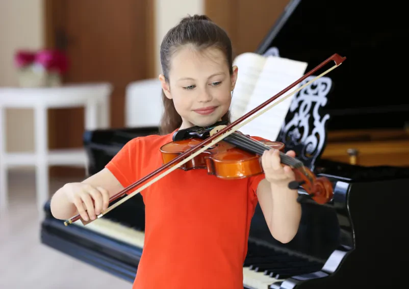 Otrok med individualno glasbeno vajo z učiteljem, ki ga uči igranja violine.