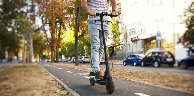 Nekdo se vozi z električnim skirojem po kolesarski stezi