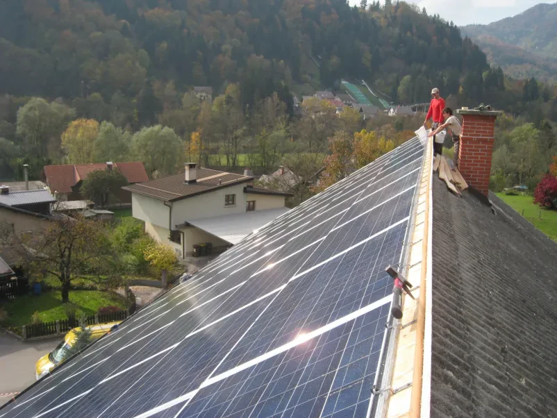 Postavitev panelov za sončno elektrarno na strehi večstanovanjskega objekta v Sloveniji.