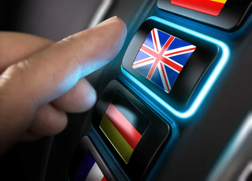 Več gumbov z različnimi zastavami na sliki, roka izbere gumb z britansko zastavo.