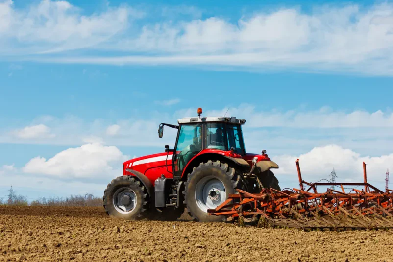 Rdeč traktor orje po zemlji