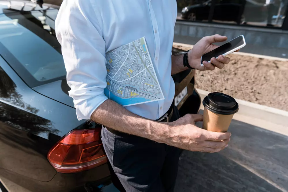 Turist z zemljevidom, kavo in mobilnim telefonom