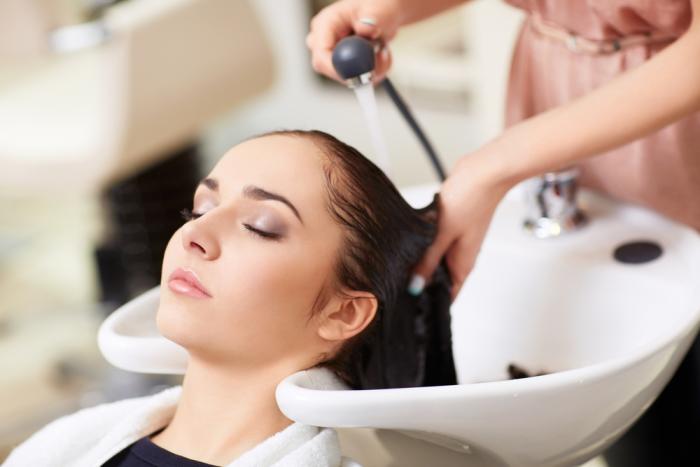 ženska med umivanjem las v frizerskem salonu