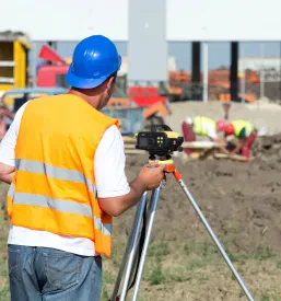 Geodet na cestnem gradbišču uporablja teodolit za natančne meritve. To je ključno za Geodetske storitve in zakoličenje objektov v Štajerski.