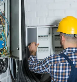 Električar v zaščitni opremi skrbno popravlja vezje v električni omarici. Zanesljive Kvalitetne elektroinštalacije Ljubljana okolica so ključnega pomena za vsak dom in podjetje.