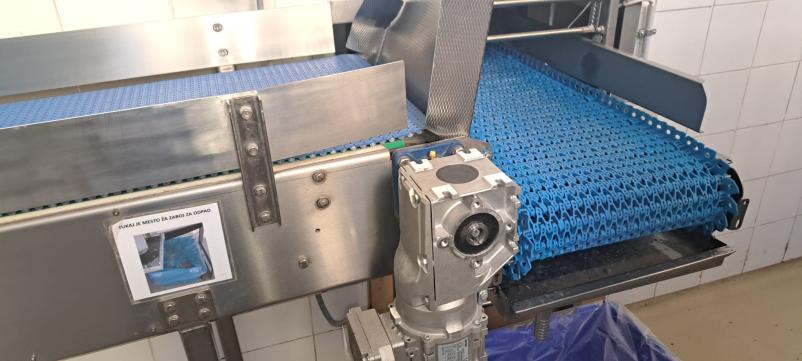 Izurjene roke delavca natančno sestavljajo kovinske komponente, kar kaže na podrobno in kakovostno izvajanje industrijske montaže.