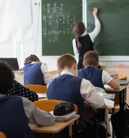 Učenka osredotočeno piše po črni tabli, kar poudarja kakovostno izobraževanje in učenje v OŠ z vrtcem Dol pri Ljubljani.