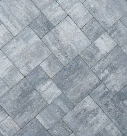 Detajl sive tlakovane površine, položene v elegantnem vzorcu ribje kosti. Prikazane so teksturne in barvne razlike, ki ustvarjajo privlačno in vzdržljivo tlakovanje tal.