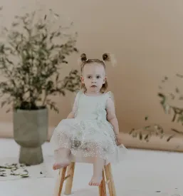 Majhen otrok z radovednim izrazom in široko odprtimi očmi, posnet v profesionalnem fotografskem studiu.