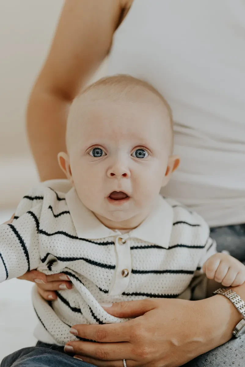 Vesela družina med profesionalnim fotografiranjem v studiu, ki zajema prisrčne trenutke. Studio fotografiranje Markovci.