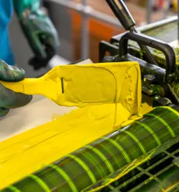 Delavec nanaša rumeno barvo na industrijski CMYK tiskarski stroj. Ta proces je ključen za kakovost tiska, ki ga nudi Tiskarna, grafično oblikovanje in digitalni tisk Muta, Koroška.