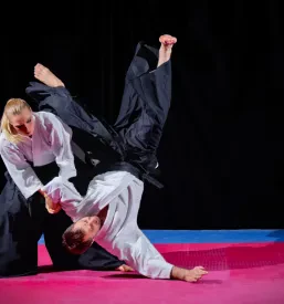 Dva aikido borca v tradicionalnih oblačilih med intenzivnim treningom in prikazom tehnike, ki je pogosta na treningih aikida Ljubljana.