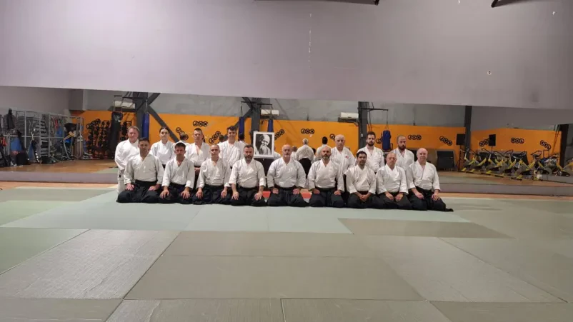 Inštruktor demonstrira aikido tehniko Izkušeni inštruktor demonstrira tehniko aikida skupini učencev. Treningi aikida Ljubljana poudarjajo pravilno izvedbo in razvoj borilnih veščin.