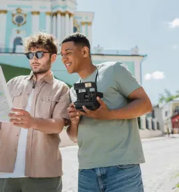 Mladi turistični vodič in afriško-ameriški turist s fotoaparatom skupaj pregledujeta mestni zemljevid.
