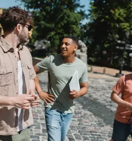 Veseli afriško-ameriški turist z zemljevidom se pogovarja z izkušenim vodičem med sprehodom po mestu.