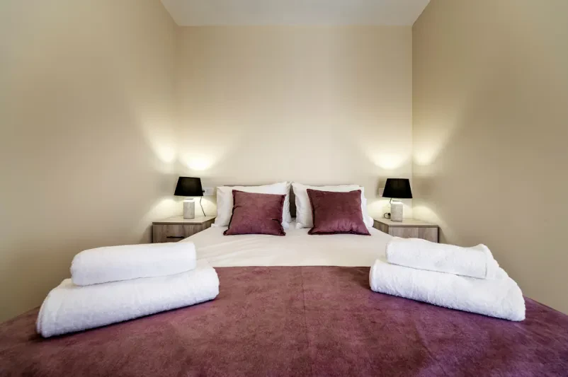 Moderna spalnica z udobno zakonsko posteljo, blazinami in nočnimi omaricami. Odličen ugoden apartma za 2 osebi Ljubljana za sproščujoč oddih.