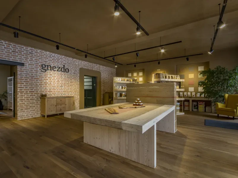 Izkušeni mojster nanaša glineni omet Mojster natančno nanaša glineni omet na notranjo steno, kar je primer tradicionalnih tehnik gradnje z naravnimi materiali in ekološkim pristopom.