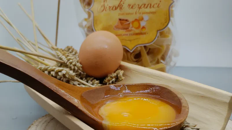 Pšenično polje za kakovostne testenine Zlato pšenično polje v sončni svetlobi, ki simbolizira naravne in sveže sestavine, uporabljene v naših testeninah.