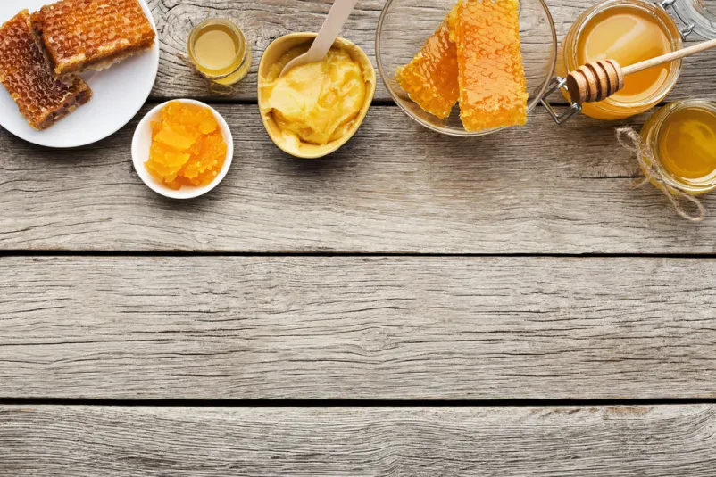 Različne vrste sladkega svežega medu Različni kozarci sladkega svežega medu so lepo razporejeni na leseni mizi. Od zgoraj je vidna bogata paleta medenih mešanic.