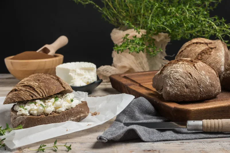 Domači kruh s skuto in timijanom Sveže pečen domač kruh s kremasto skuto in aromatičnim timijanom, pripravljen po tradicionalni kmečki recepturi.