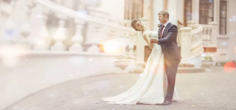 Mladoporočenca se objemata pred impresivno fasado starega dvorca, kar ustvarja elegantno in brezčasno vzdušje za portrete.