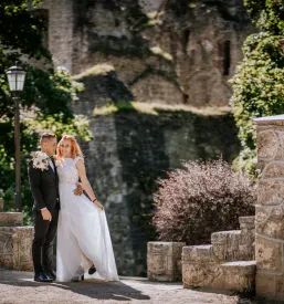 Romantičen par pozira ob stari kamniti steni in lučeh. Prikazuje čaroben trenutek za družinsko in poročno fotografiranje Gorenjska.