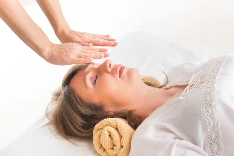 Profesionalna reiki terapevtka izvaja zdravljenje pri mladi ženski, kar predstavlja pomemben del ponudbe energetskih terapij v Pomurju.