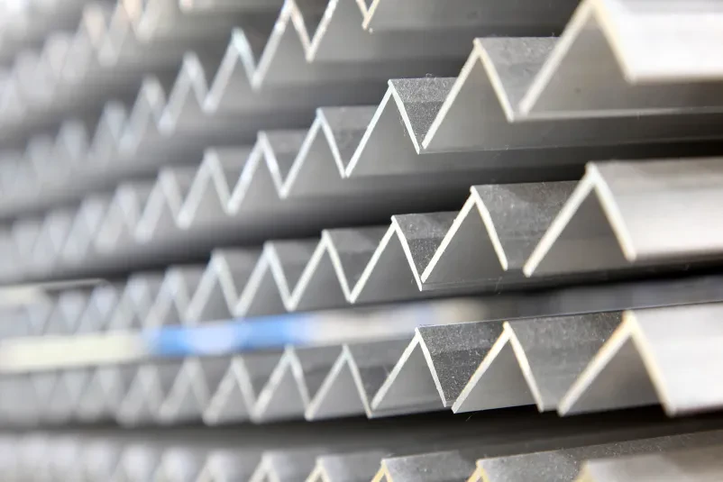 Delavec s fokusom obdeluje aluminijasti material na CNC stroju v svetli in urejeni tovarni, kar zagotavlja visoko kakovost izdelkov.