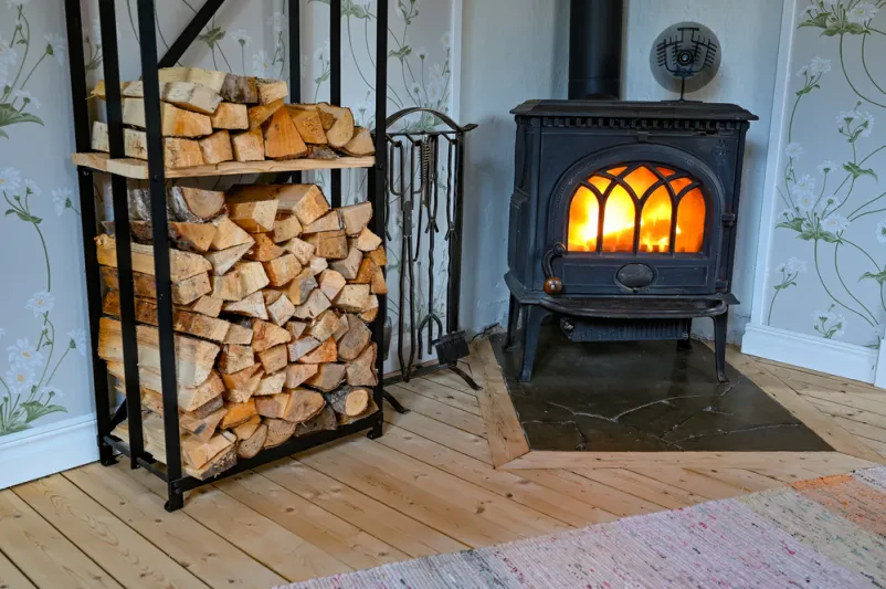 Učinkovita litoželezna peč z zgornjim ventilatorjem Črna litoželezna peč z majhnim ventilatorjem na vrhu, ki učinkovito razporeja toploto po celotnem prostoru.