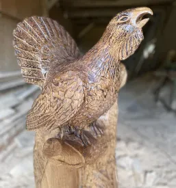 Zelo detajlna lesena skulptura medveda, izklesana iz masivnega lesa, poudarja teksturo krzna in moč te živali.