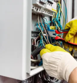 Delavec popravlja omarico s kleščami. Za Kvalitetno obnovo in servis elektroinštalacij Ljubljana, okolica, je to nujno.