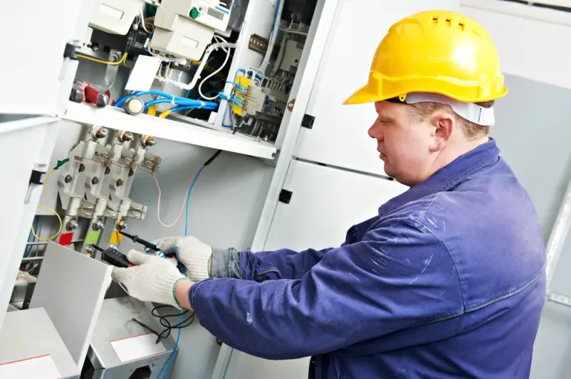 Izkušen električar preverja napetost v distribucijski omarici, kar zagotavlja kvalitetne elektroinštalacije Šentjernej, novo mesto.