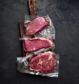 Sveži, vakuumsko pakirani kosi govedine, kot sta rib-eye in stegno, so pripravljeni za prodajo, del Kvalitetnih mesnih izdelkov Brezovica, Osrednja Slovenija.