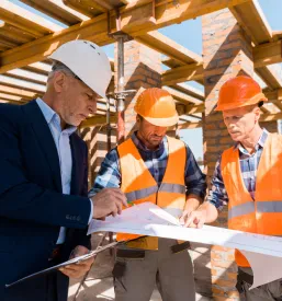 Trije moški, vključno z arhitektoma, pregledujejo gradbene načrte. Ključno za kvalitetno arhitekturno projektiranje Tabor, Savinjska, Štajerska.