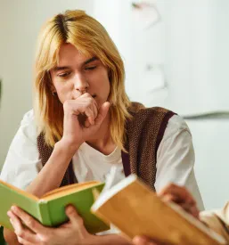 Mladi moški na kavču ob kavi sproščeno razpravljajo o knjigah, izmenjujejo si misli in ideje v domačem okolju.