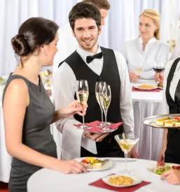 Natakar nudi osvežilne prigrizke in pijačo udeležencem poslovnega dogodka, kar kaže na kakovosten catering za dogodke.