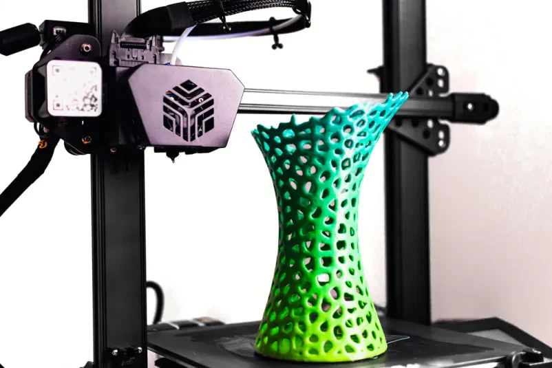 Proces 3D tiskanja vaze z večbarvno PLA nitjo, ki tvori edinstven in vizualno privlačen personaliziran izdelek iz plastike.