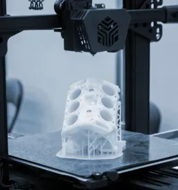 Bel prototip avtomobilskega motorja, natisnjen iz plastike na 3D tiskalniku, ponazarja sodobno aditivno tehnologijo izdelave in inženiringa.