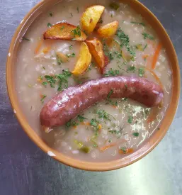 Okusen ričet s klobaso, postrežen v Planinskem domu Ig Ljubljana, je priljubljena izbira med domačimi jedmi na žlico za obiskovalce.