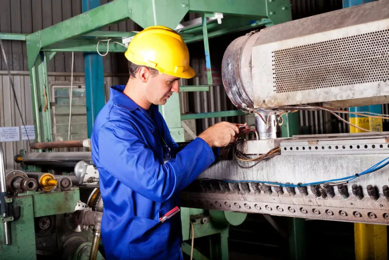Izkušen industrijski mehanik skrbno popravlja in vzdržuje kompleksni stroj v tovarni. Njegovo delo je ključno za nemoteno delovanje proizvodnje.