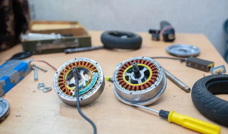 Natančen posnetek mehanika med delom na kolesu električnega skuterja, kjer menja električni motor, poudarja popravilo.