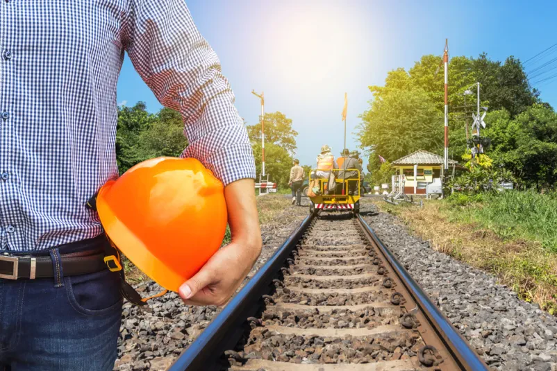 Inženir z rumeno čelado in ekipo na motornem vozičku pregleduje industrijske tire. Redni pregledi so ključni za vzdrževanje.