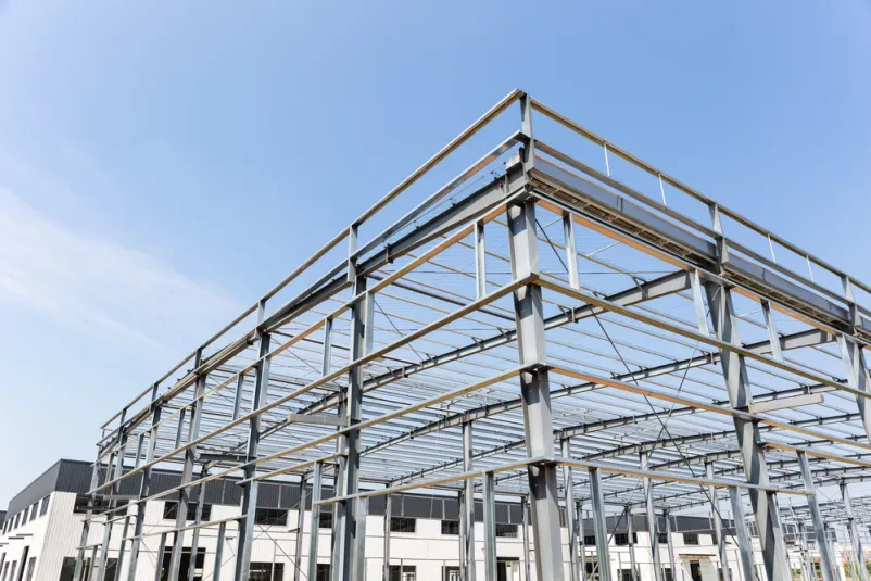 Gradnja industrijske stavbe z jekleno konstrukcijo Jeklena konstrukcija tovarne v gradnji. Natančni statični izračuni za jeklene konstrukcije so ključni za stabilnost in varnost industrijskih objektov.