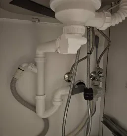 Detajlni pogled na urejen sifon in vodovodne priklope pod kuhinjskim koritom. Zanesljive vodovodne inštalacije.