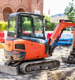 Kompaktni gosenični bager izvaja dela na območju cestnih gradbišč, pri čemer je ključen zanesljiv in ugoden servis mini bagrov Goriška, Slovenija.