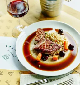 Nasmejana gostja uživa v okusni jedi in sproščenem vzdušju našega bistroja. Poudarek na posamezni izkušnji in prijetnem obisku.